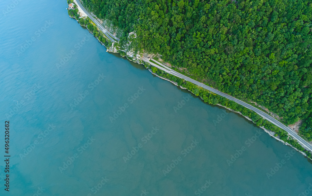 Aerial view of an amazing road on the coast line next to a river. Beautiful roads infrastructure around the world during a beautiful summer day.
