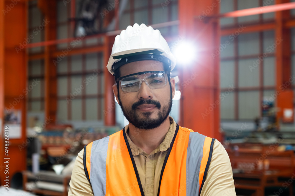 Selective focus at Caucasian men engineer supervisor, wearing safety equipment. While doing audit for quality and safety control inside of factory area. With blurred background of heavy machine. Selective focus at Caucasian men engineer supervisor, wearing safety equipment. While doing audit for quality and safety control inside of factory area. With blurred background of heavy machine.