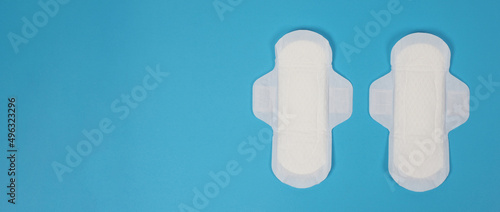 Woman sanitary napkins on blue background. Top view. Absorbent pads worn by women to absorb menstrual blood. Comfortable white sanitary napkins arranged on light blue paper. Represent Hygiene concept