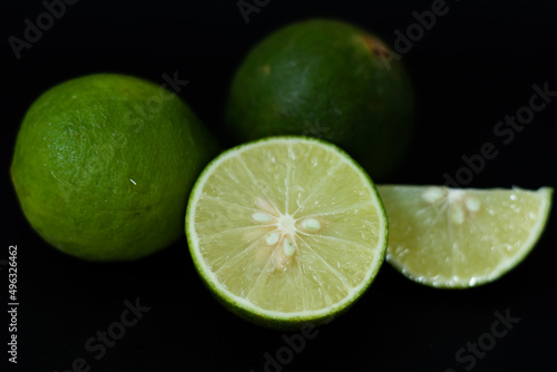 Fresh lime with green skin and black background.