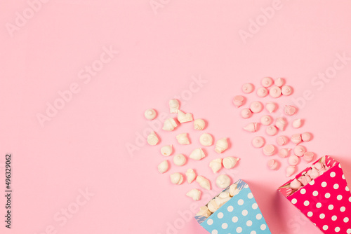 Merengues rosas y blanco dentro de un cono de cartón celeste y rosa sobre un fondo rosa pastel liso y aislado. Vista superior. Copy space © Mercedes Fittipaldi