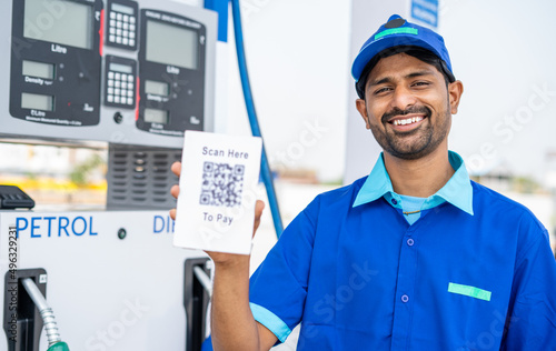 Photos rack focus shot of petrol pump worker showing scan here to pay qr code for payment by looking at camera - concept of online or contact less payment at technology gas filling station