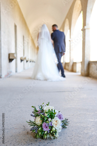 bouquet di fiori in primo piano e sposi in lontananza sfocati che camminano photo