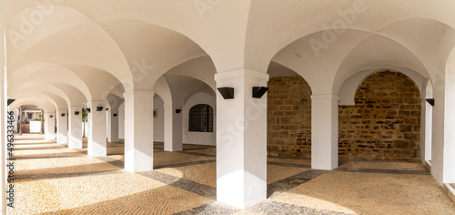whitewashed portico with many arches and a patterned stonework floor photo