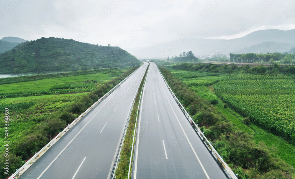 Empty highway through green fields