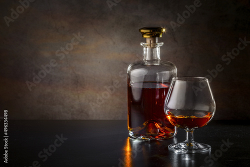 A glass of cognac, cognac in a bottle on a dark background. Copy space