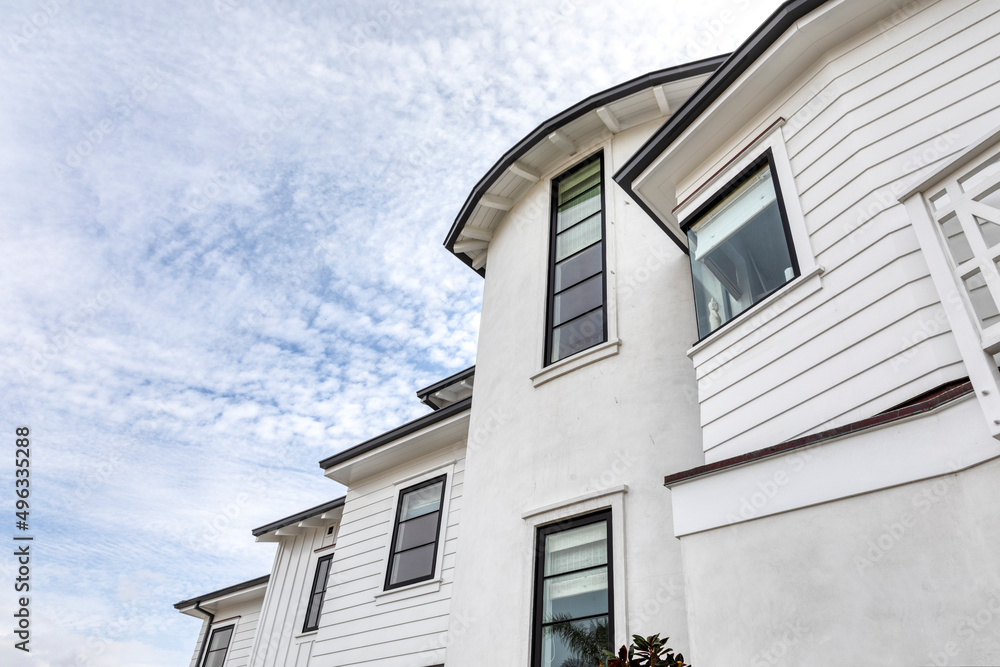 Façade of a white house that has two stories and lots of windows. Bright sunny day.