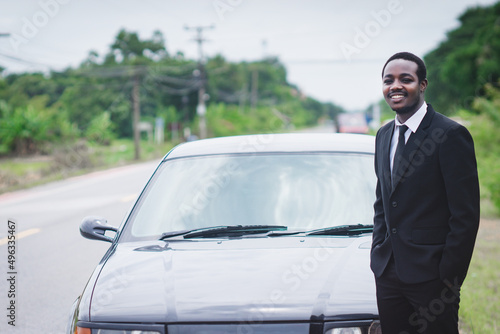 Confident african businessman in suit standing with his car