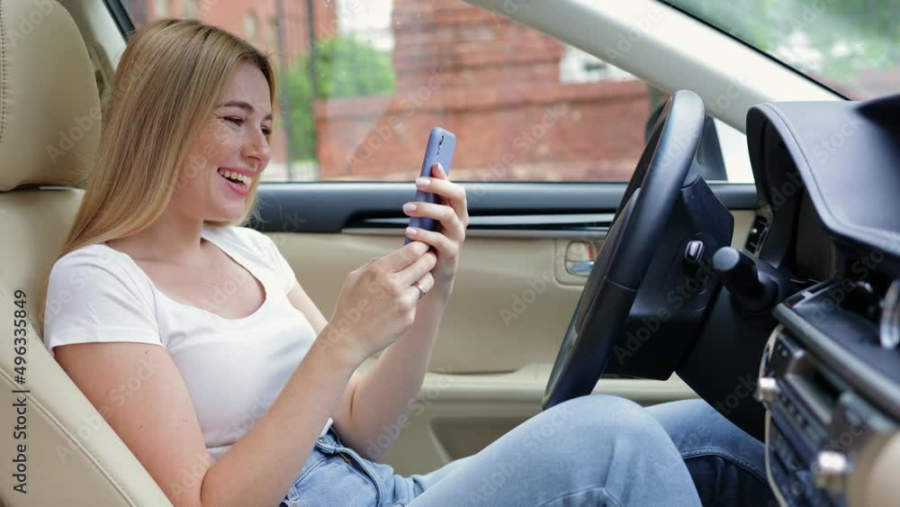 positive cheerful pleasant joyful optimistic triumphant girl using mobile phone sitting in the car.