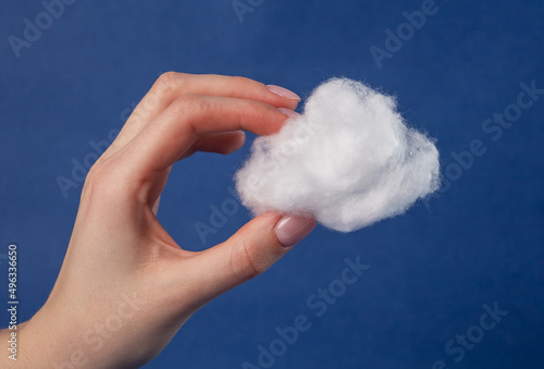 Hand with cotton cloud on blue sky background. Surrealism. Imagination, fantasy concept. Windy, cloudy weather. High quality photo