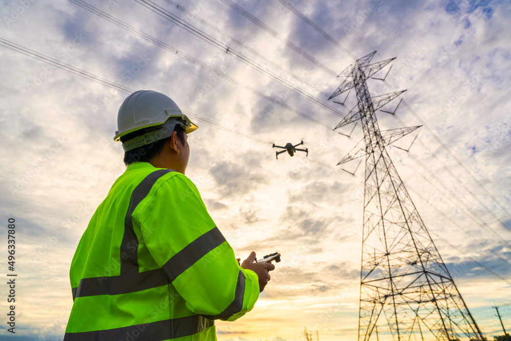 Asian engineer location use drone to fly inspections at the electric power station to view the planning work by producing electricity high voltage electric transmission tower at sunset. Asian engineer location use drone to fly inspections at the electric power station to view the planning work by producing electricity high voltage electric transmission tower at sunset.