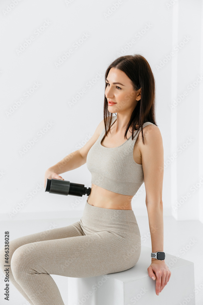 Athletic young woman massaging abs with hand massage gun, post-workout recovery. Physical therapy. Athletic young woman massaging abs with hand massage gun, post-workout recovery. Physical therapy.