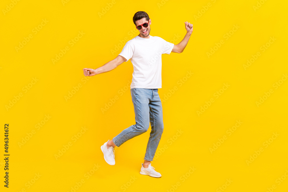 Full size photo of funny millennial brunet guy dance wear eyewear t-shirt jeans sneakers isolated on yellow background Full size photo of funny millennial brunet guy dance wear eyewear t-shirt jeans sneakers isolated on yellow background