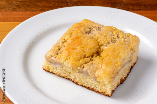 Slice of banana cake on a white plate on a wooden table.