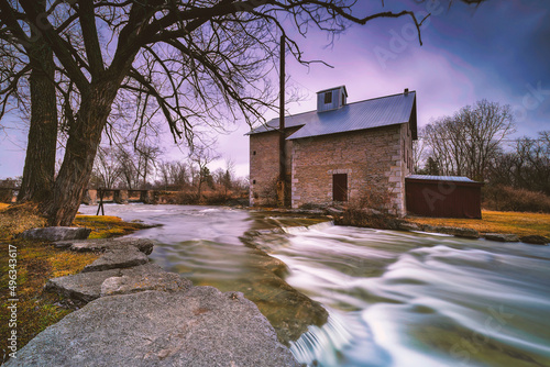 The old Babcock Mill and Cascade in Odessa Ontario Canada featuring long exposure and moving water with stunning cloud features and old buildings.  