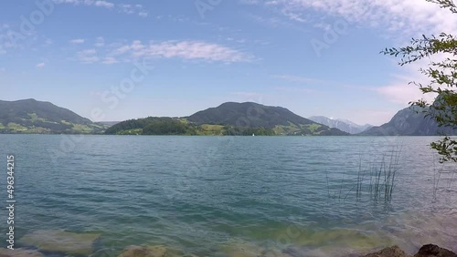 awsome lake in austria named mondsee with mountains, waving reeds, wavy water a sunny day with a blue sky and a little sailboat all in all a georgous summer day photo