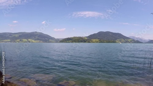 incredible lake in austria named mondsee with mountains, waving reeds and wavy water a sunny day with a blue sky all in all a georgous summer day photo