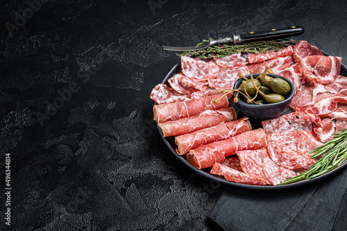 Italian Antipasto set platter, cured meat plate with Prosciutto crudo, Salami and Coppa Sausage. Black background. Top view. Copy space