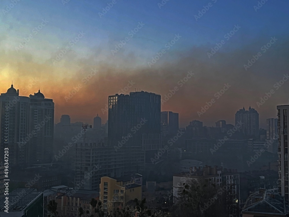 Kyiv city capital of Ukraine in acrid fire smoke after explosion in early morning. Lights were turned off in the houses due to the curfew. View through the glass of the window.
