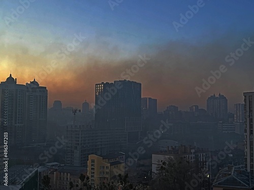 Kyiv city capital of Ukraine in acrid fire smoke after explosion in early morning. Lights were turned off in the houses due to the curfew. View through the glass of the window.