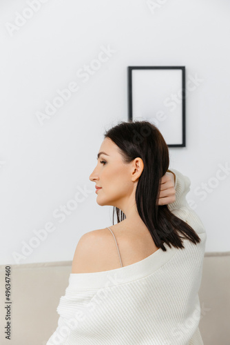 Portrait of a Caucasian woman, side view, in her home clothes against the background of the interior. 