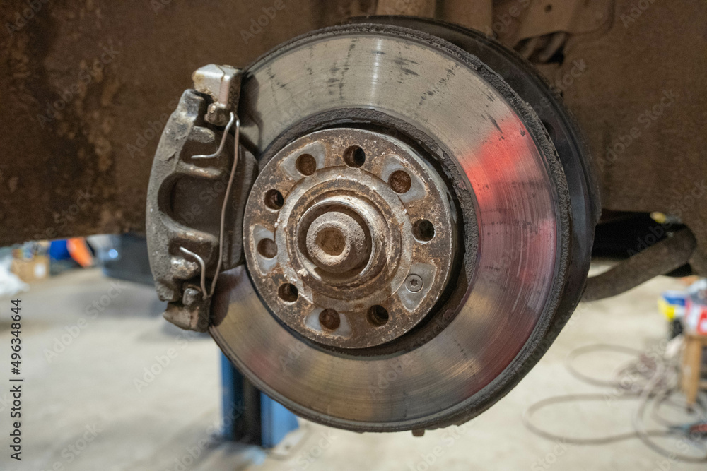 Disc brake of the vehicle for repair, in process of new tire replacement. Car brake repairing in garage.Close up.