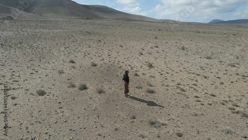 Aerial view of a person walking in a desert valley with mountain in background near Caleta de Famara, Lanzarote, Canary Islands, Spain. photo
