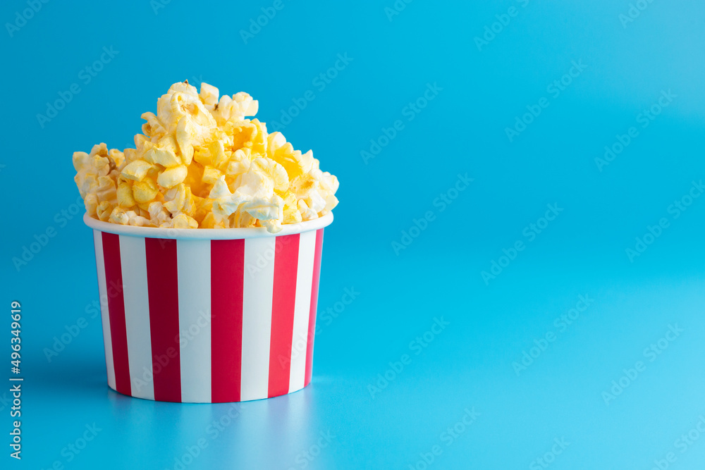 Butttery Popcorn in a Red and White Striped Container on a Blue Background Butttery Popcorn in a Red and White Striped Container on a Blue Background