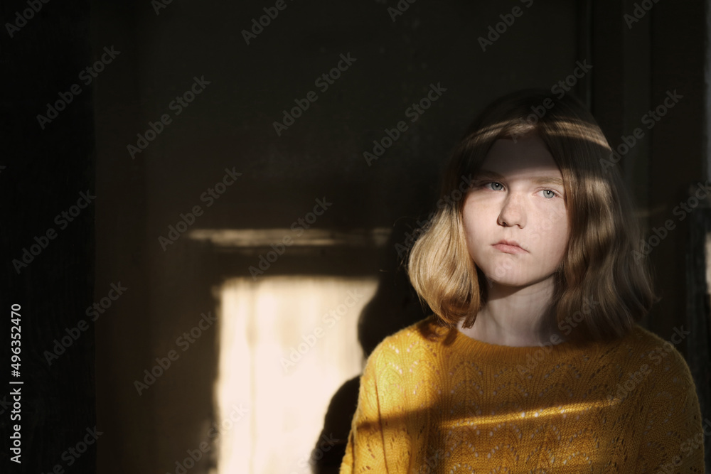 young sad teen girl on background wall in sunlight