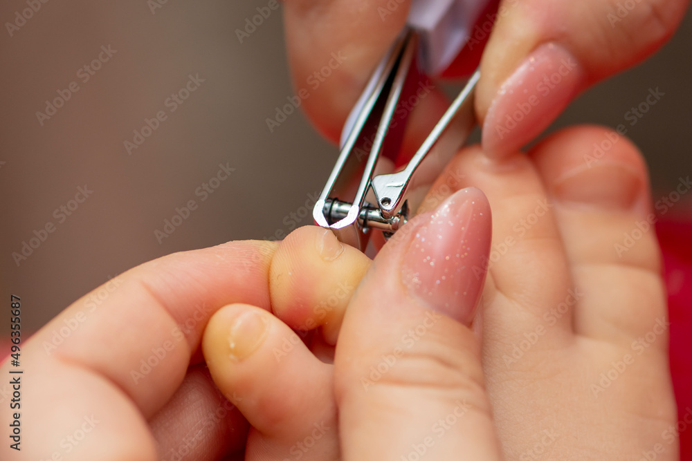 Mom cuts the toenails of the child with nail tongs, close-up, selective focus.