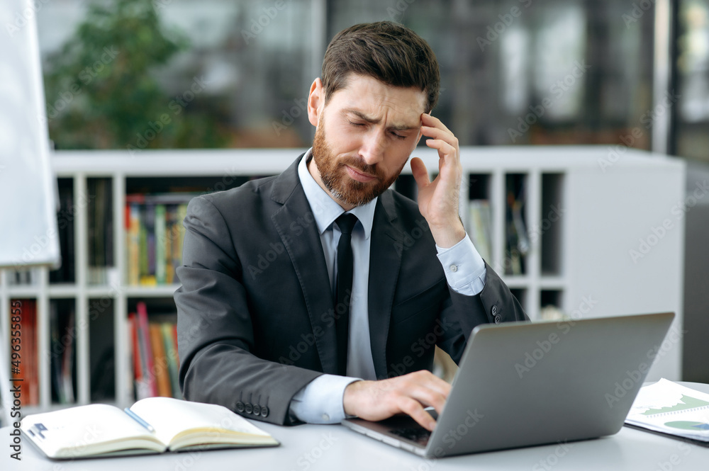 Overworked, tired, caucasian businessman, company owner, financial consultant, sits at a desk in front of a laptop, closes his eyes, has a headache, massages the temple, needs a rest or a break Overworked, tired, caucasian businessman, company owner, financial consultant, sits at a desk in front of a laptop, closes his eyes, has a headache, massages the temple, needs a rest or a break