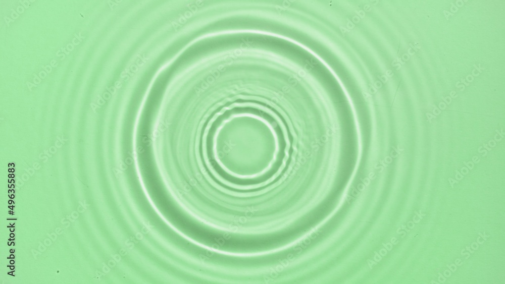 Drop falls down on water surface creating rings on green background | Beauty background shot for skin care cosmetics commercial Drop falls down on water surface creating rings on green background | Beauty background shot for skin care cosmetics commercial