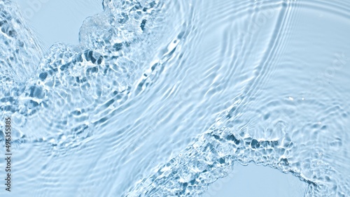 Water flows from opposite sides creating waves and ripples on light blue background | Background shot for skincare products commercial