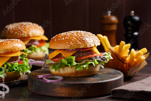 Trois burgers classiques fait maison sur une planche rustique avec des frites