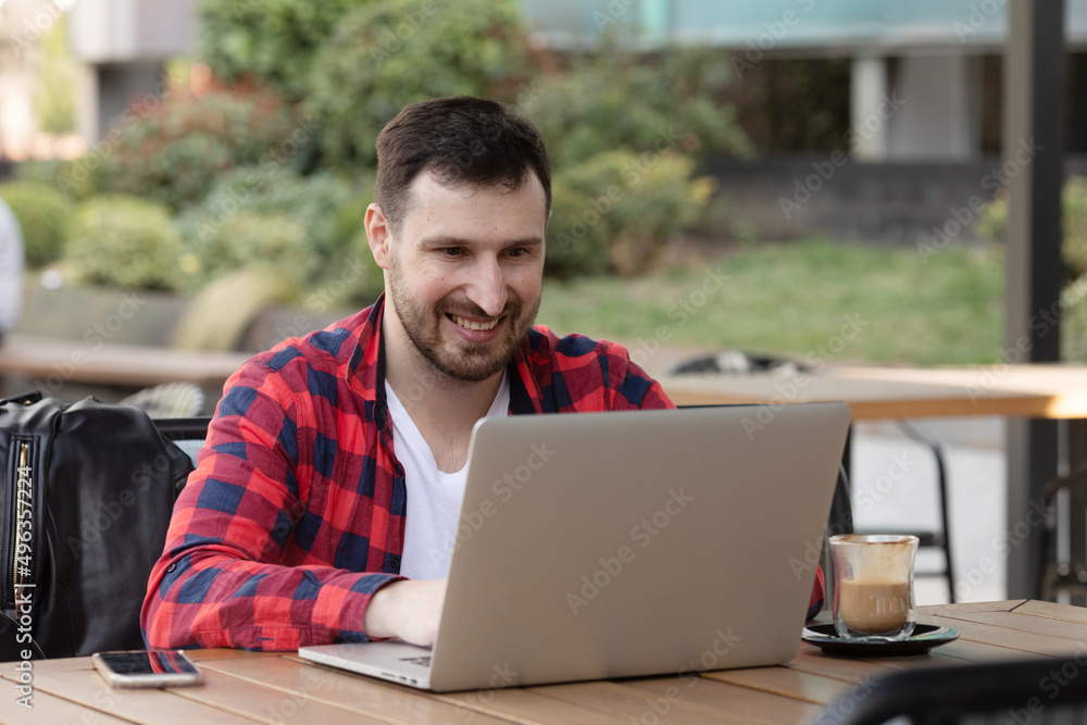 Smiling man surfing the net on laptop while drinking coffee in a bar. Smiling man surfing the net on laptop while drinking coffee in a bar.
