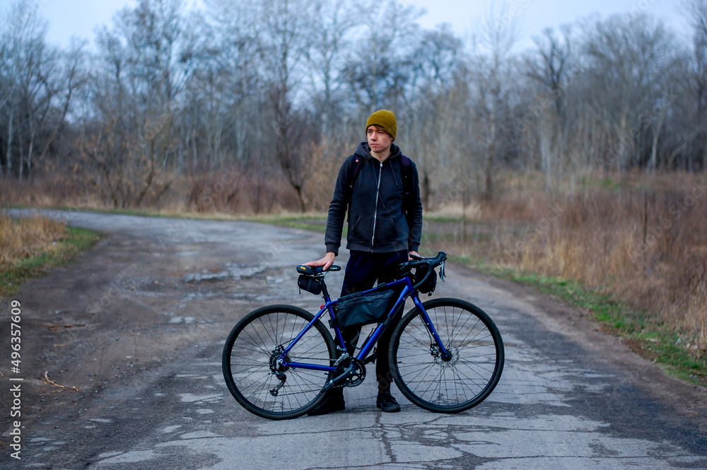 Middle-aged guy cyclist in the forest in spring in cloudy weather. Road bike. gravel bike. bike rides. travel light. healthy lifestyle Middle-aged guy cyclist in the forest in spring in cloudy weather. Road bike. gravel bike. bike rides. travel light. healthy lifestyle