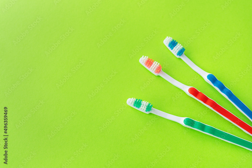 Multicolored toothbrushes on a green background, the concept of dental care and oral hygiene. Place for an inscription.