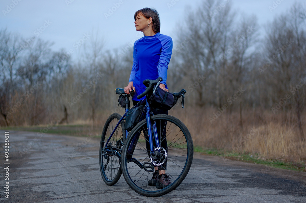 a middle-aged woman rides a gravel bike outside the city. healthy lifestyle. cycling travel. active lifestyle.