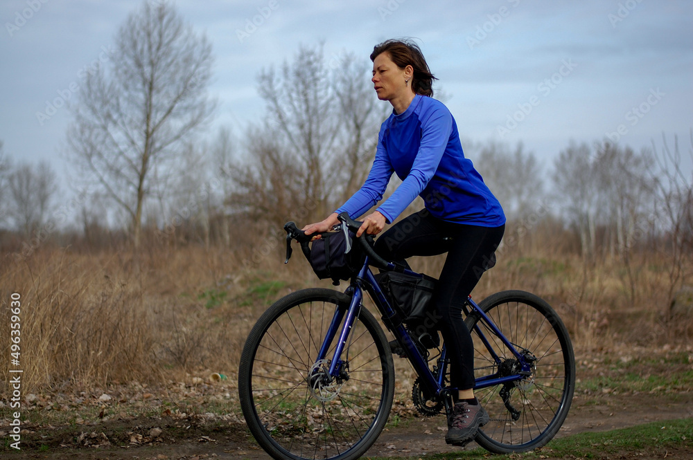 a middle-aged woman rides a gravel bike outside the city. healthy lifestyle. cycling travel. active lifestyle.