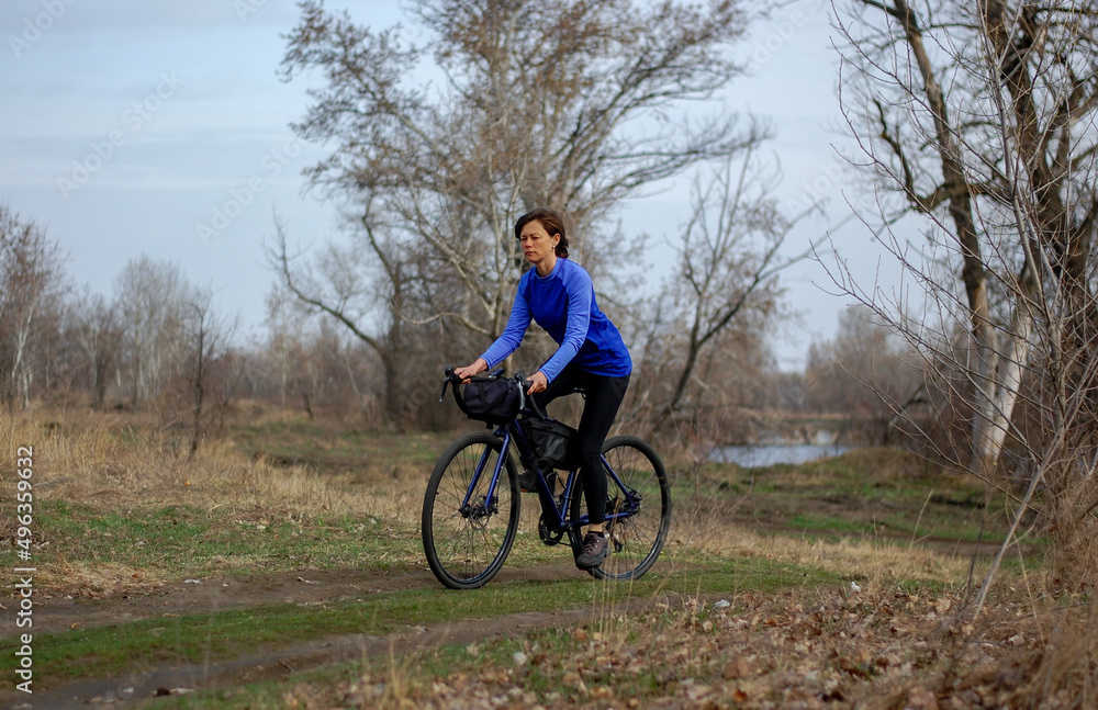 a middle-aged woman rides a gravel bike outside the city. healthy lifestyle. cycling travel. active lifestyle. a middle-aged woman rides a gravel bike outside the city. healthy lifestyle. cycling travel. active lifestyle.