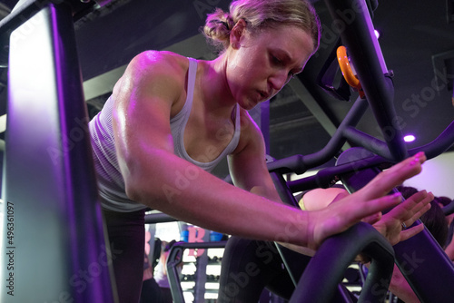 Muscular young woman working out on exercise machine. 