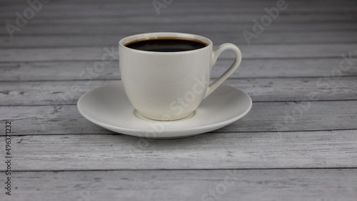 White cup of coffee on a wooden table, close-up