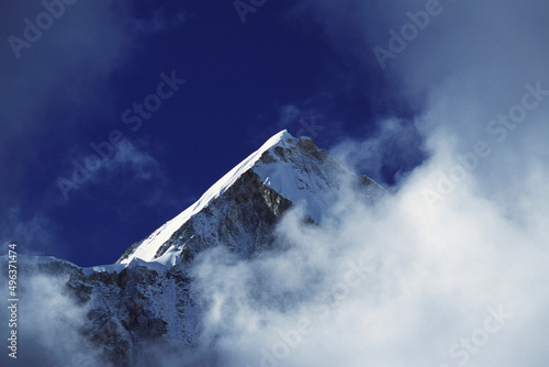 Low angle view of a mountain peak surrounded by clouds, Mount Lingtren, Nepal photo