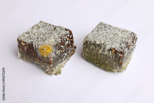 Yellow and green mold with spores on spoiled, rotten cakes. Close up color macro photo with isolated disgusting food on white background.