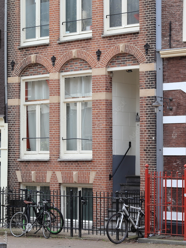 Amsterdam Street View with Brick House Facade Close Up, Parked Bicycles and Metal Fence, Netherlands