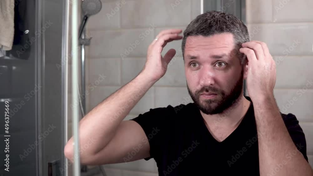 man examines himself in the mirror