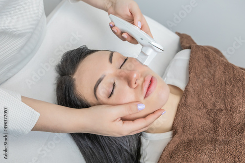 Dermatologist performing a facial analysis and diagnosis on a beautiful woman lying down.Detailed scanning of skin hydration, sebum, acne, wrinkles, sensitivity and melanin. Beauty concept and trend.