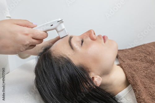 Dermatologist performing a facial analysis and diagnosis on a beautiful woman lying down.Detailed scanning of skin hydration, sebum, acne, wrinkles, sensitivity and melanin. Beauty concept and trend.