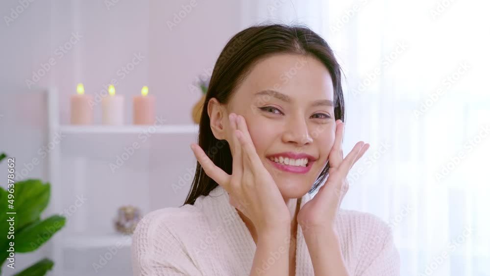 Happy beautiful woman in white bathrobe applying moisturizing cream on face , skin care and treatment concept Happy beautiful woman in white bathrobe applying moisturizing cream on face , skin care and treatment concept