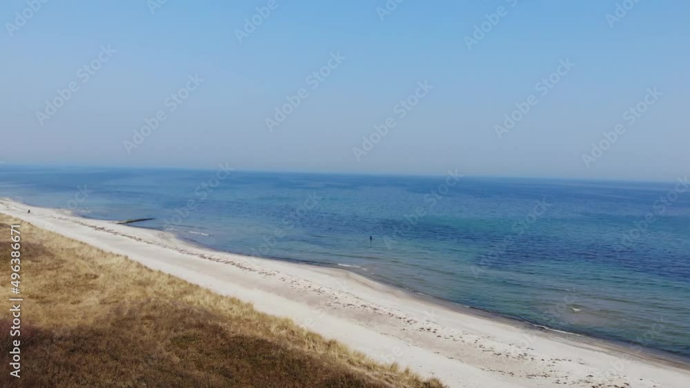 Luftaufnahme von Angler mit Angel in Wathose im Wasser bei Sonne watend per Drohne gefilmt als Fahrt über Strand Luftaufnahme von Angler mit Angel in Wathose im Wasser bei Sonne watend per Drohne gefilmt als Fahrt über Strand